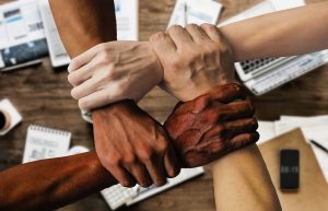 four different skin colour hands holding each others wrist to show diversity